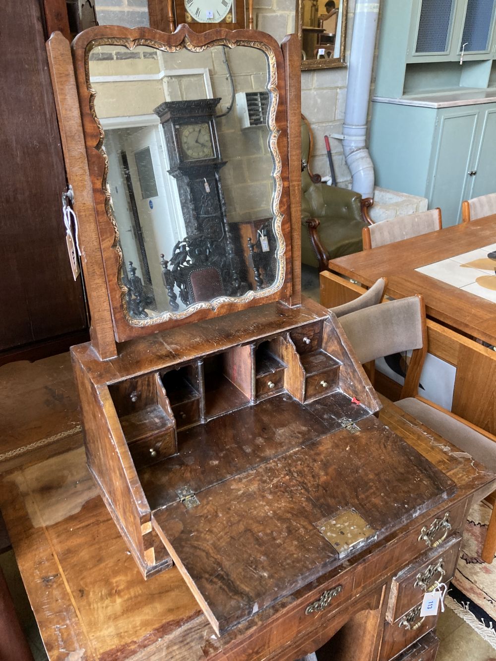 An early 18th century walnut toilet mirror, the base enclosed by fall front over drawer, width 46cm, depth 30cm, height 74cm